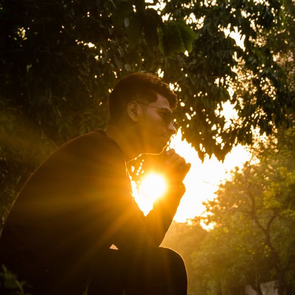 Person meditating peacefully in a serene natural environment at sunset.